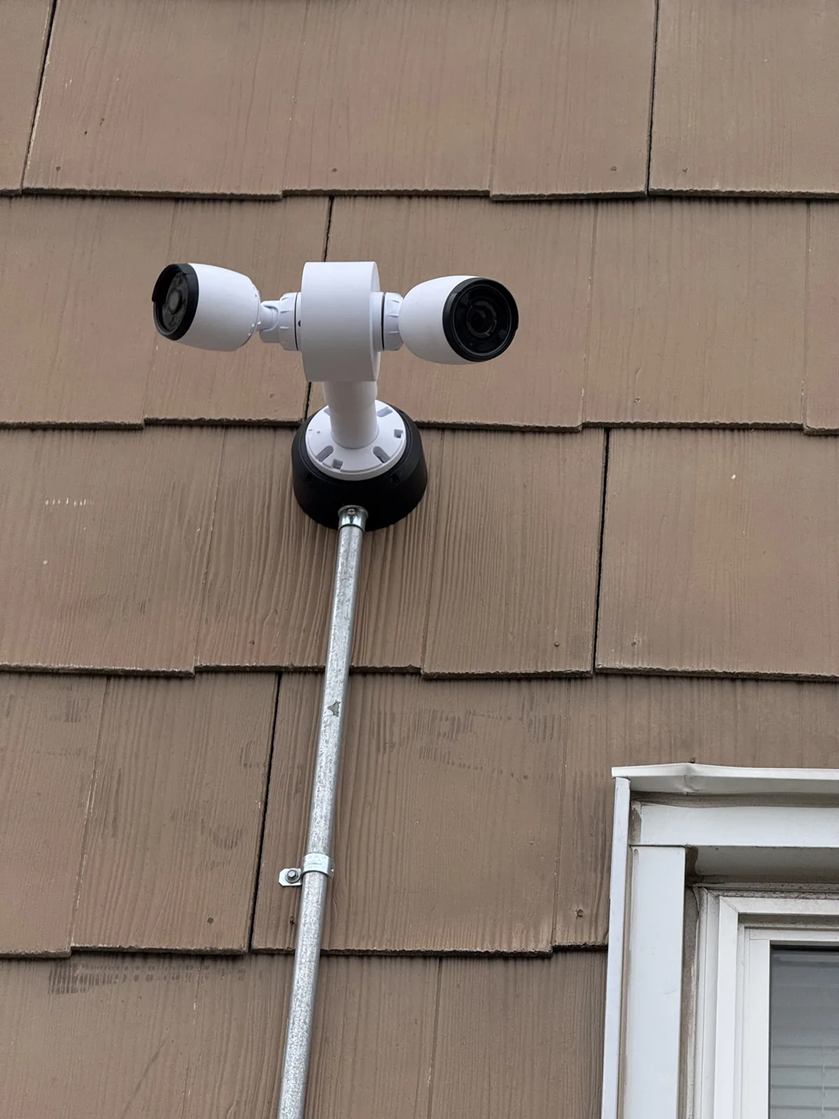 Two exterior security cameras on a house